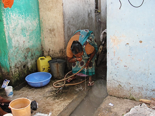 A woman at Shakti Nagar slum drinking water from a polluted source.