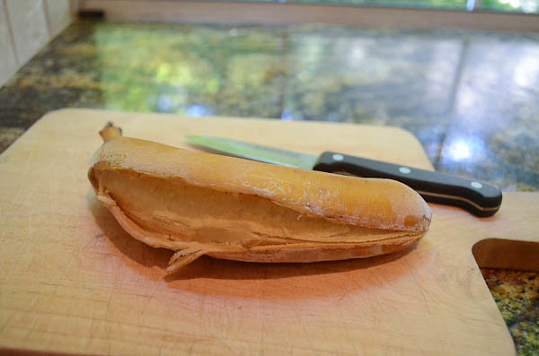 A frozen banana, sliced open lengthwise on a cutting board with a knife.