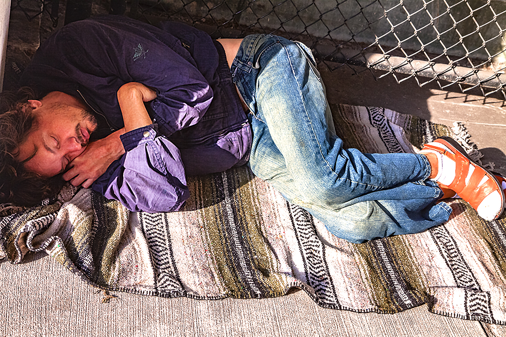 Man-in-sandals-sleeping-outside-parking-garage--Orlando