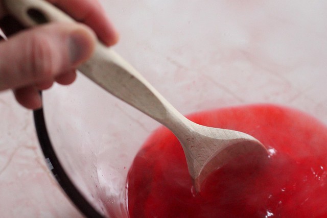 hand with spoon making jello in a bowl. 