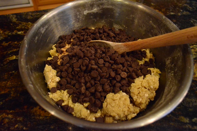 Chocolate chips and toffee bits being added to the mixture of cookie ingredients.