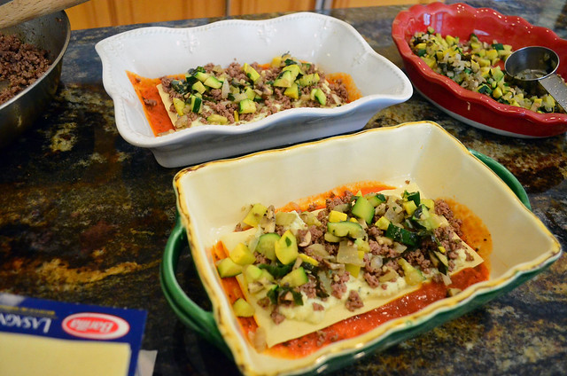 Cooked veggies being added to the partially assembled lasagna.