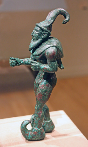 Striding figure with ibex horns, a raptor skin draped around the shoulders, and upturned boots