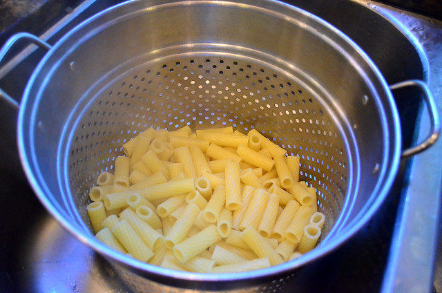 Cooked rigatoni in a pasta strainer.