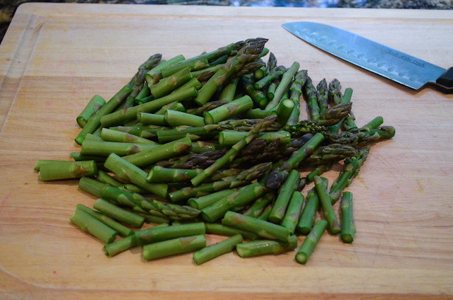 Asparagus stalks are cut on a cutting board.