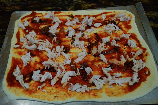 Shredded chicken is added to the top of the pizza.