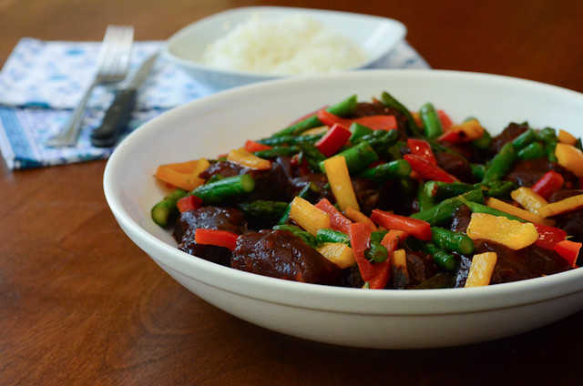 The cooked ribs and stir fried vegetables are placed in a white serving bowl.