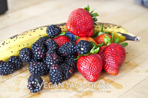 blackberries, strawberries, and a banana on a cutting board