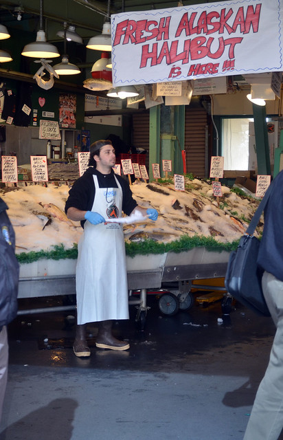 A man standing in front of a fish stall selling fresh fish.