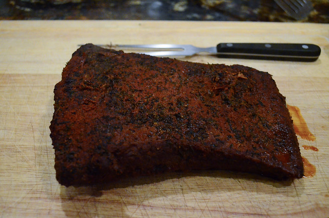 The beef brisket is placed on a cutting board.