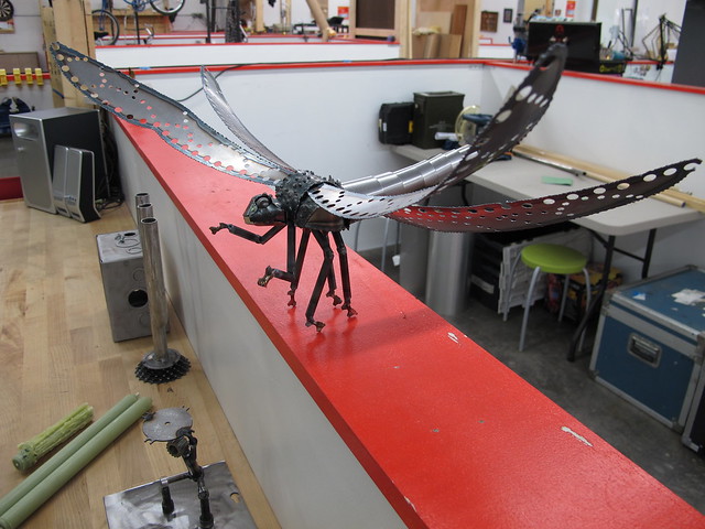 metal dragonfly on a red shelf