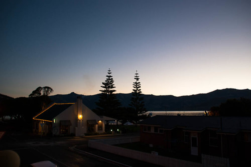 trees houses sunset sea newzealand sky water night buildings lights hills southisland bankspeninsula akaroa