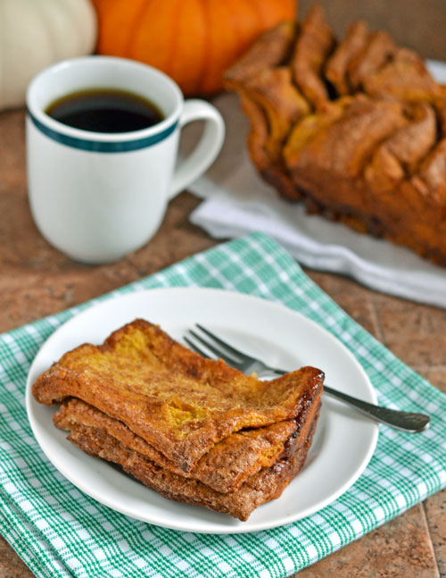 A slice of Pumpkin Pull Apart Bread on a white plate with a fork and striped napkin
