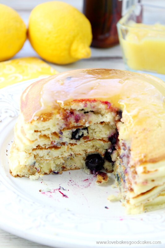 Lemon Berry Pancakes stacked up on a plate with a section removed.
