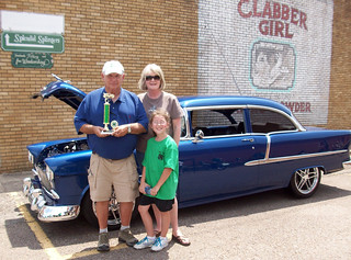 Picture of family holding a Best in Show trophy next to an antique car in 2012.