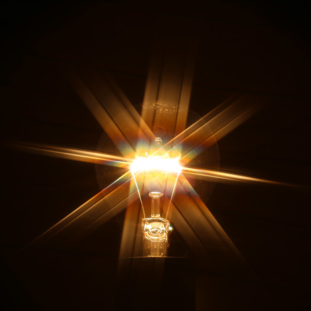 Glowing light bulb with rays of light