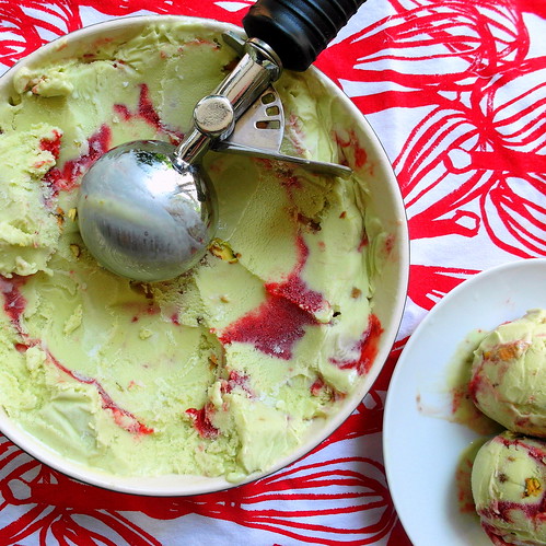 square overhead image of a round container of avocado ice cream with a red swirl