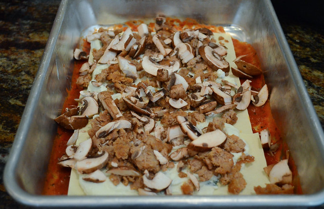 Cooked sausage and mushrooms are spread across the pasta sheets.