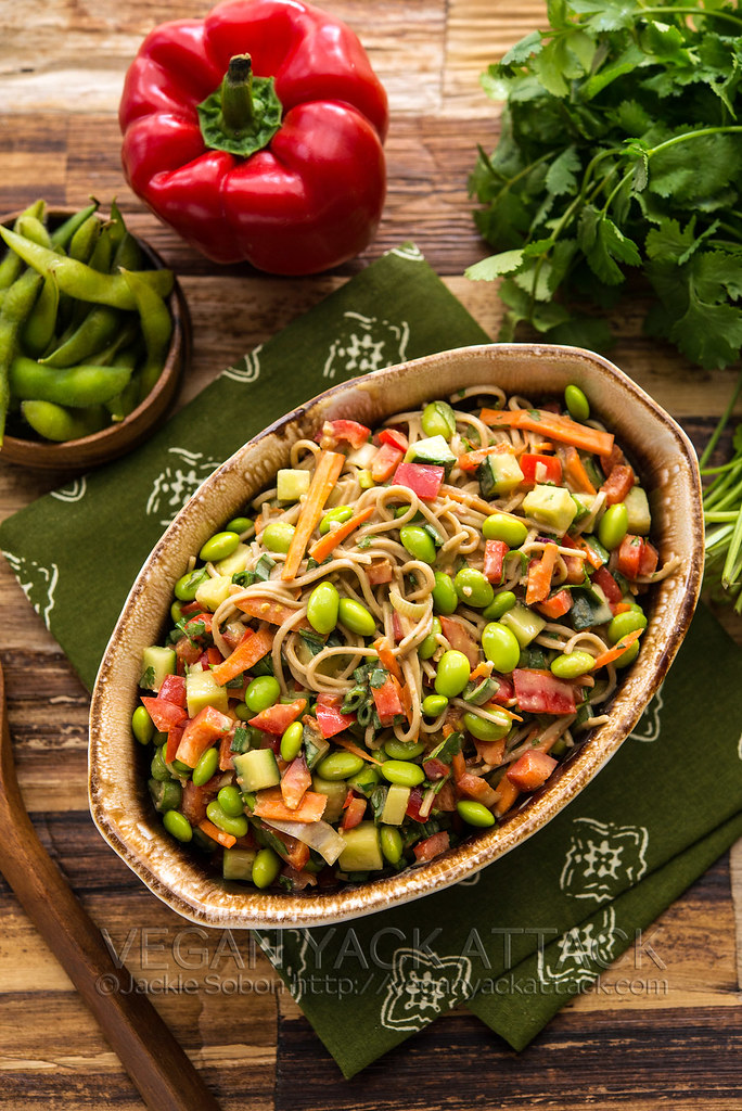 Oval bowl filled with edamame noodle salad on green linen