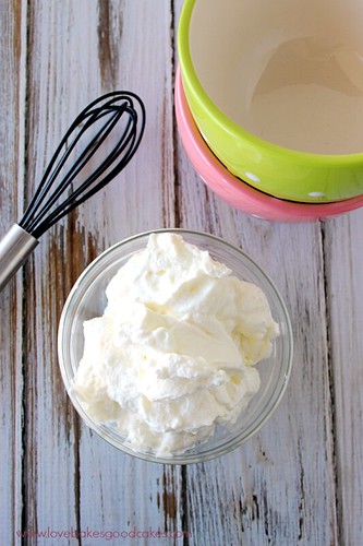 Homemade Sweetened Whipped Cream in a bowl with a whisk looking down.