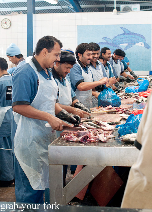 Fishmongers filleting fish at Dubai Fish Market in Deira