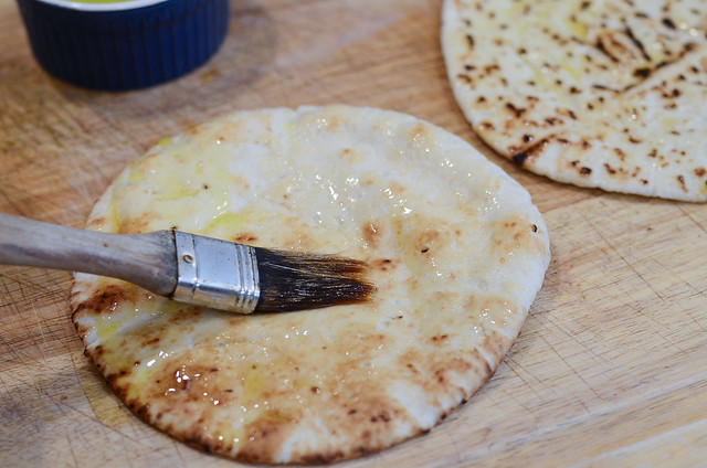 Olive oil is brushed on to a pita bread.