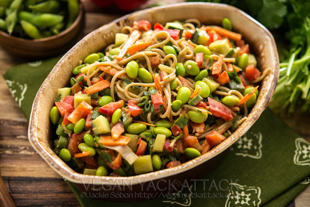 Oval bowl filled with edamame noodle salad on green linen
