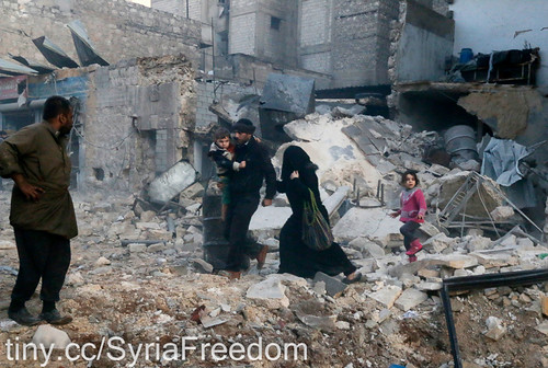 People walk on rubble of collapsed buildings at a site hit by what activists said was barrel bombs dropped by government forces in Aleppo's Dahret Awwad neighborhood January 29, 2014.