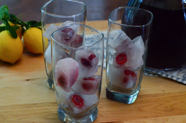 The lemonade ice cubes are placed in some glasses.