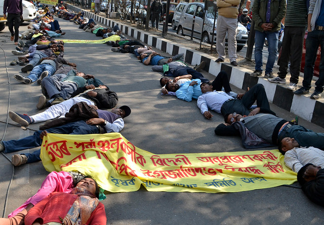 The activists of KMSS lay down on the road in protest against the tag of 'immigrant' on Northeastern people on BJP's vision document, in Guwahati on Wednesday.