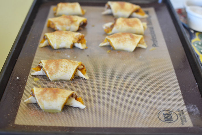 Once all of the pumpkin rugelach are rolled up, place the rugelach on a parchment lined cookie sheet, pointy-side down and brush with egg wash and sprinkle with cinnamon sugar.