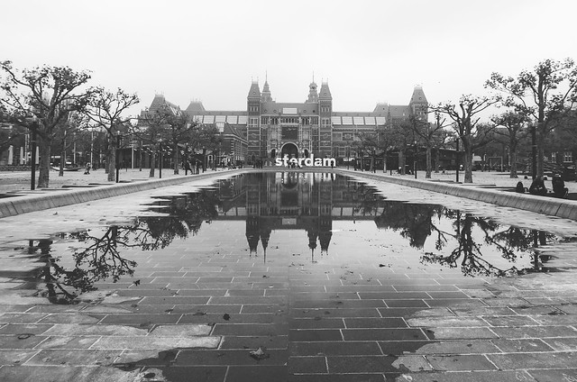 The Rijksmuseum and I Amsterdam sign reflect in puddles along Amsterdam's Museumplein.