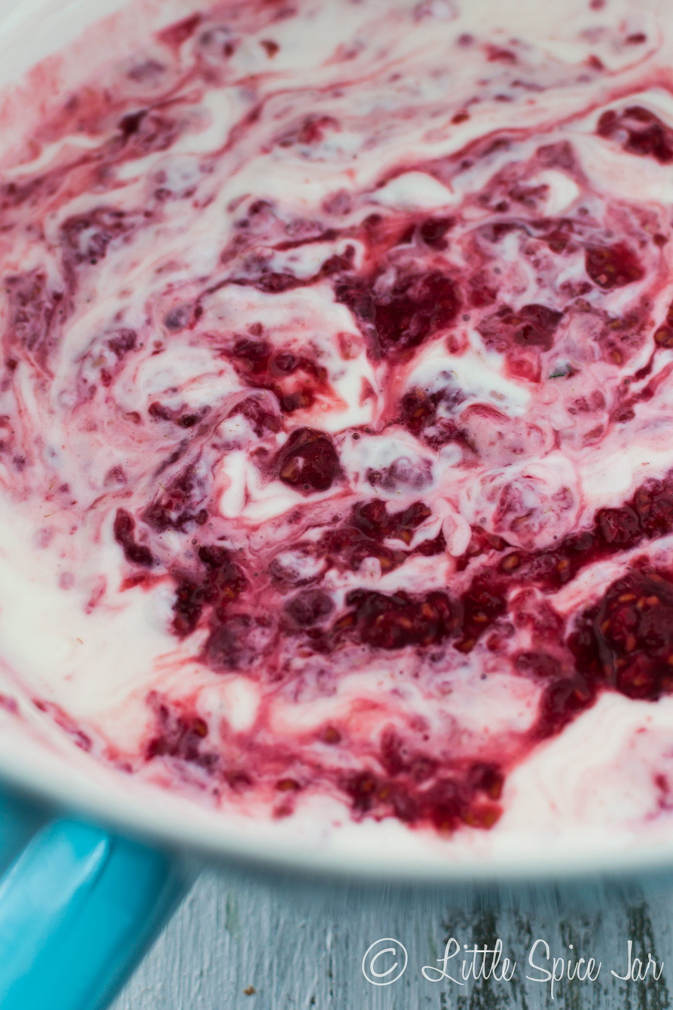 Greek yogurt mixture swirled with pureed raspberries in bowl