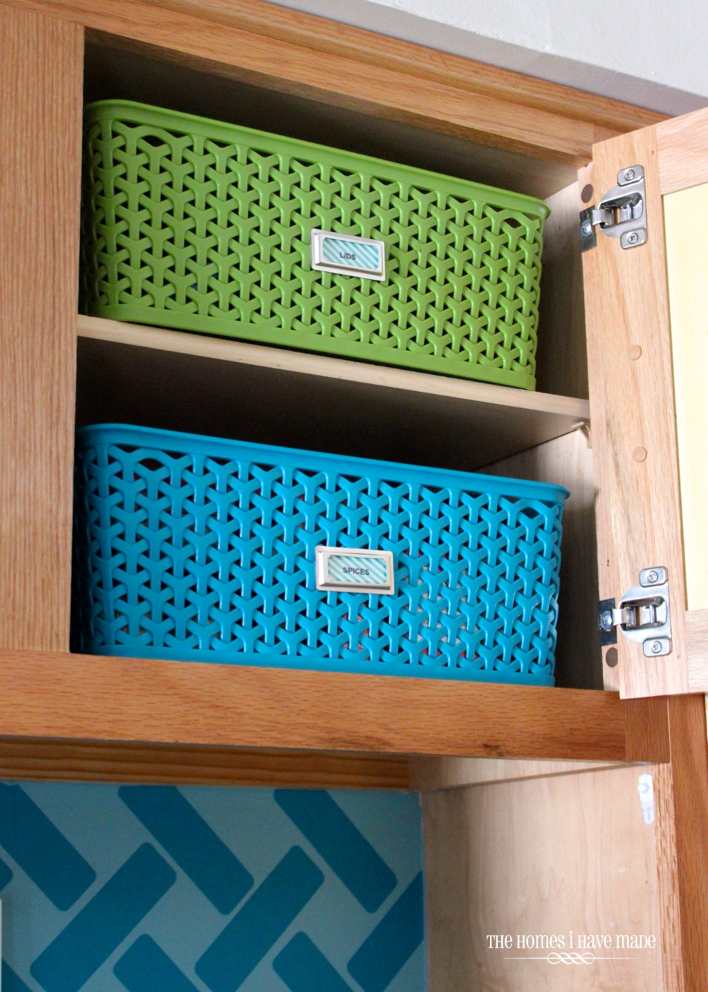 Green and blue baskets inside a little upper kitchen cabinet