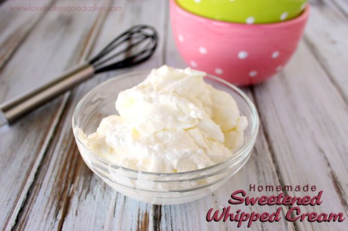 Homemade Sweetened Whipped Cream in a clear bowl with a whisk and two other bowls.