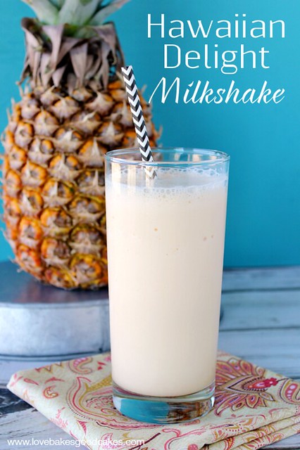 Hawaiian Delight Milkshake in a glass with a straw and a pineapple in the background. 