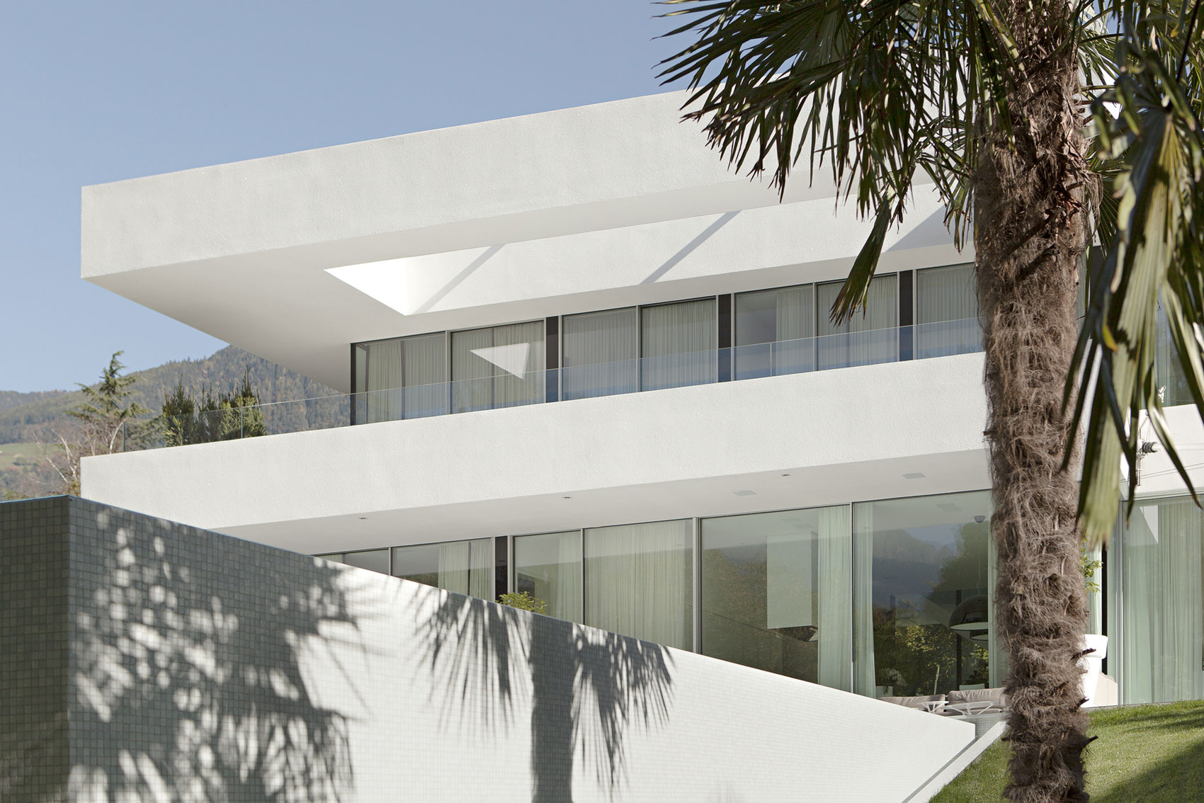 white-exterior-modern-glass-house-design-with-glass-railings-for-balcony