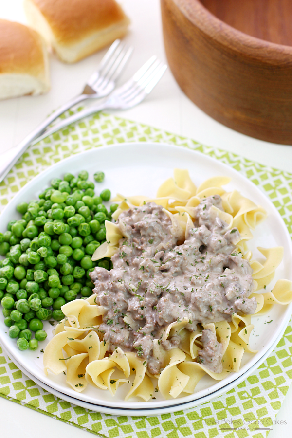Hamburger Stroganoff on a white plate with green peas and forks.