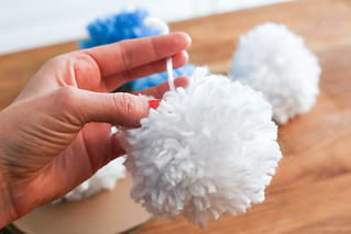 white Christmas pom pom decorations held in a hand