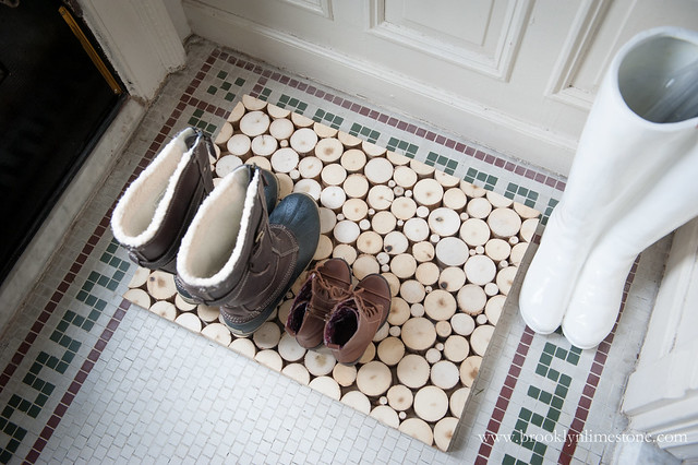 Close up overhead photo of wood slice DIY Doormat holding 2 pairs of boots with room for more