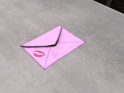 Image Description: Pink letter with a lipstick mark on the corner, on a mostly empty table.