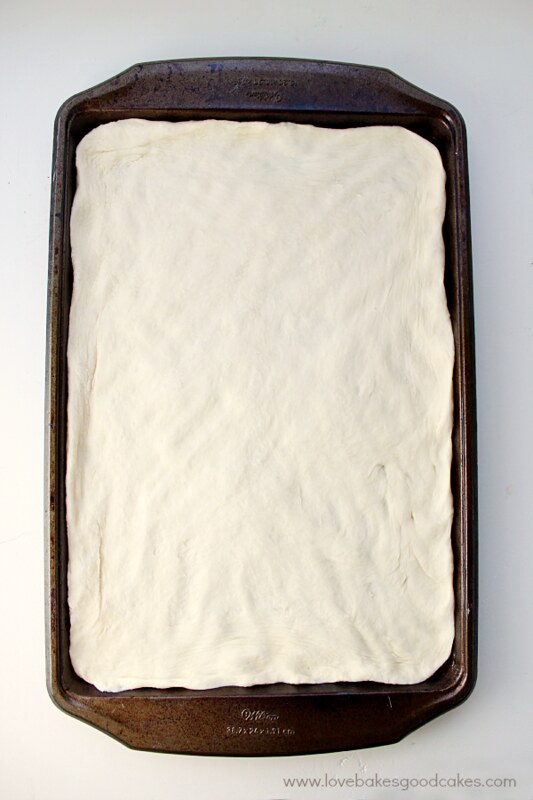 Dough being put into a baking pan and flattened out and left to rise.