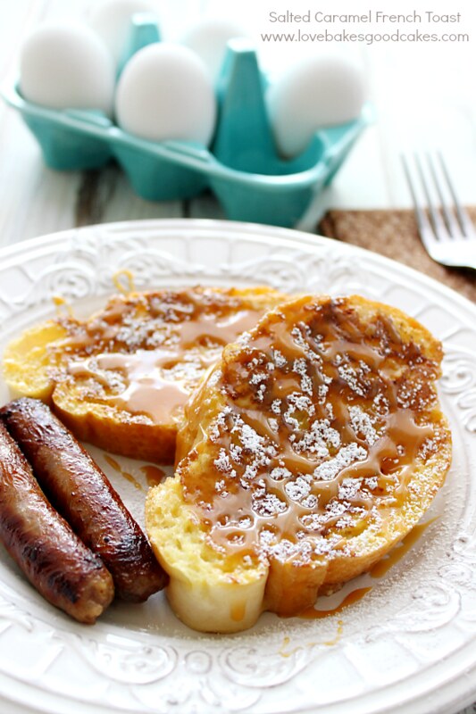 Salted Caramel French Toast and sausage on a plate with a small carton of eggs and a fork.