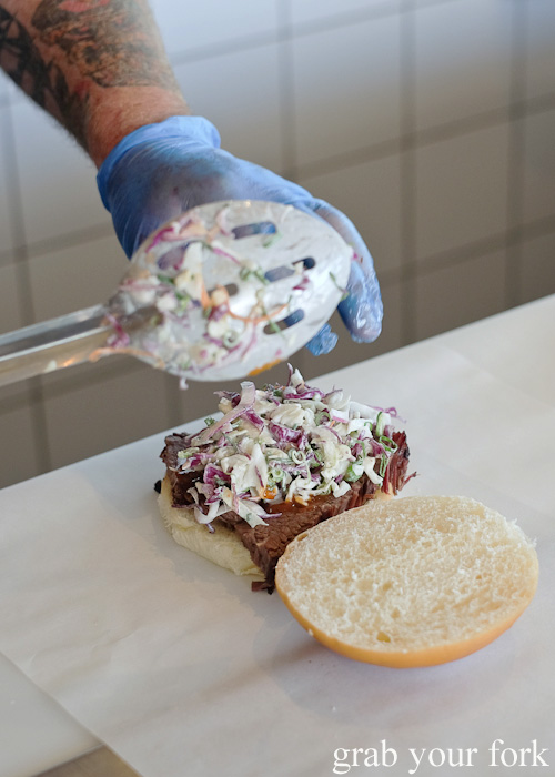 Adding slaw to the beef brisket sandwich at Vic's Meat Market at Sydney Fish Market, Pyrmont