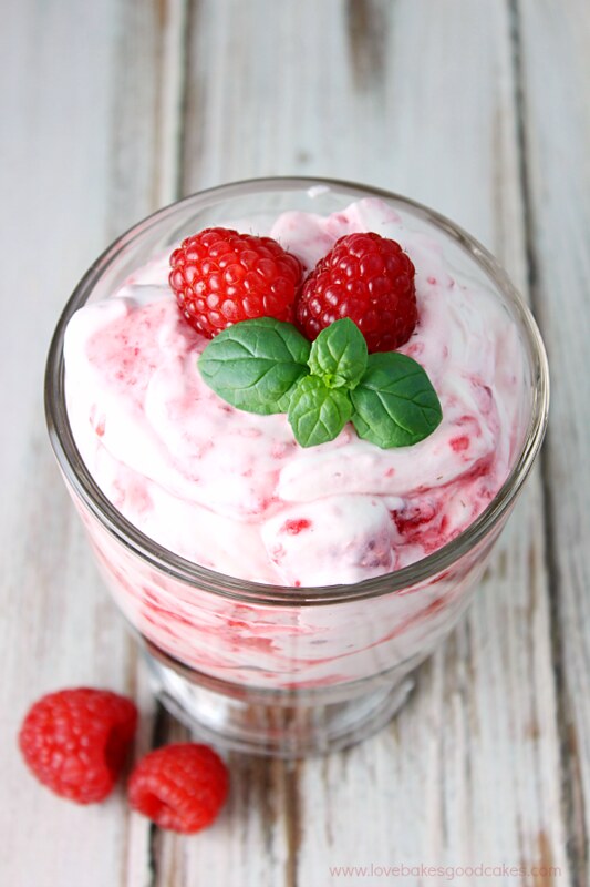 Raspberry Fool in a glass bowl with fresh raspberries on top.