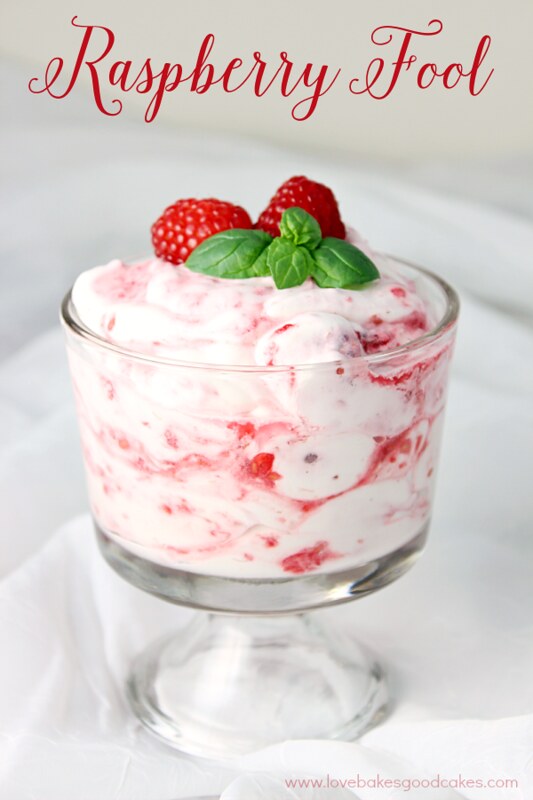Raspberry Fool in a glass bowl with fresh raspberries on top.