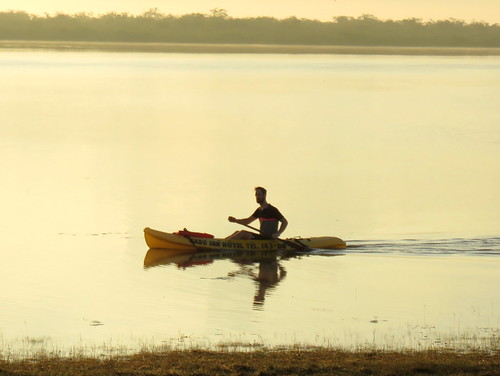 man tree rural sunrise belize lagoon canoe crooked