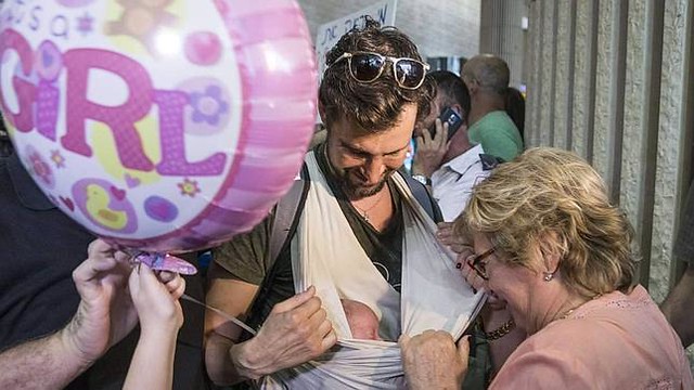 Un gai israelí muestra uno de los bebés nacidos en Nepal de madre de alquiler, a su llegada al aeropuerto de Tel Aviv