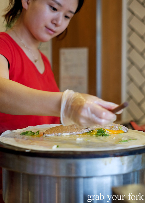 Spreading the raw egg across the jianbing pancake at Mr Bing, Chippendale