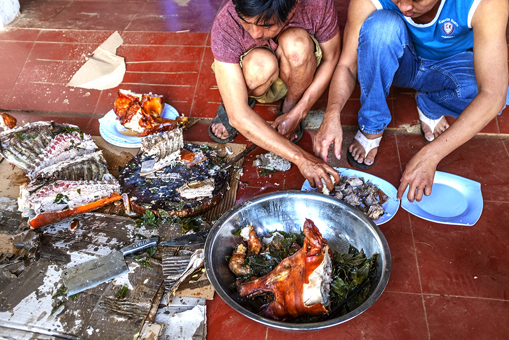 Two men preparing roast pig for neighborhood feast--Ea Kly